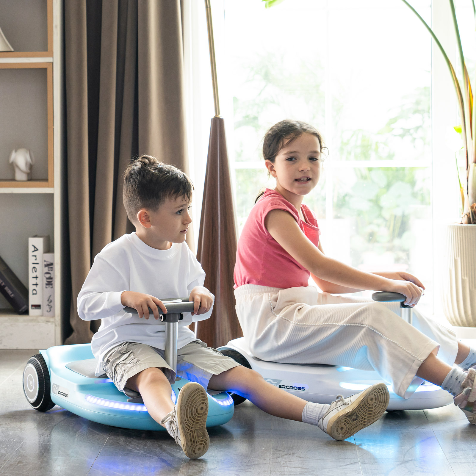 Zwei Kinder fahren Hoverkarts drinnen. Ein Junge in weißem Hemd, ein Mädchen in Pink.