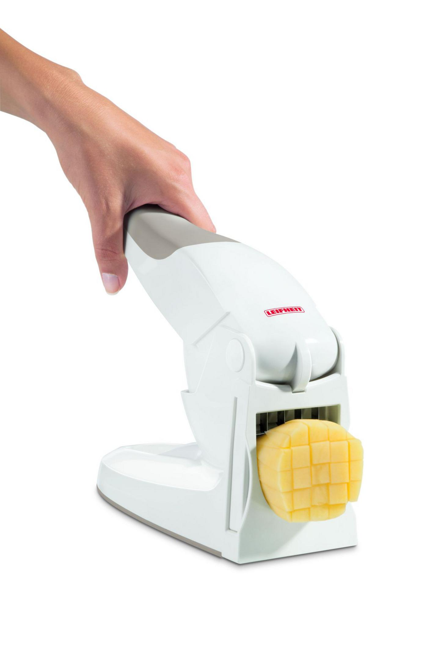 Una mano tiene un taglia patate bianco con mezza patata a cubetti.