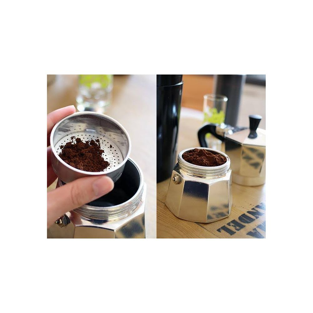 Dodawanie kawy mielonej do srebrnej kawiarki na drewnianym stole.