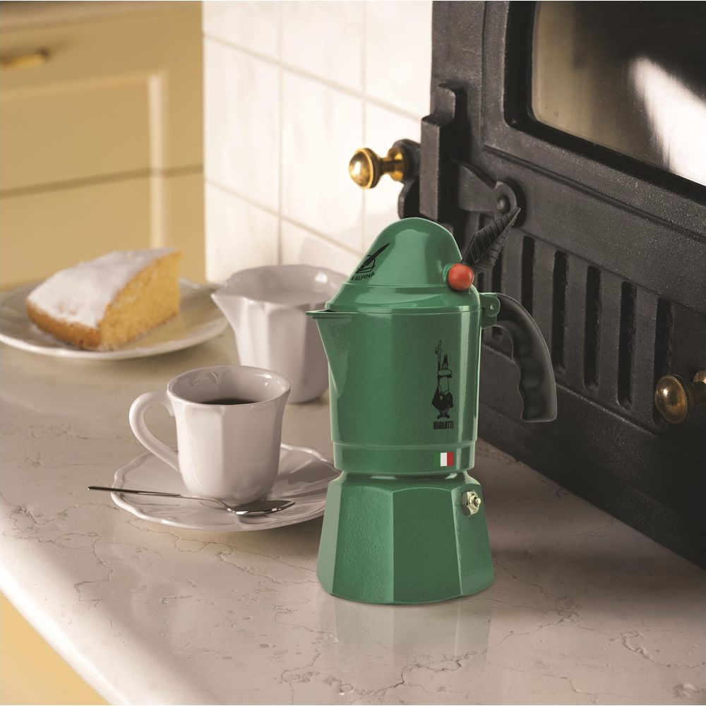 Zielona kawiarka z kawą, ciastem i cukierniczką na marmurowym blacie.