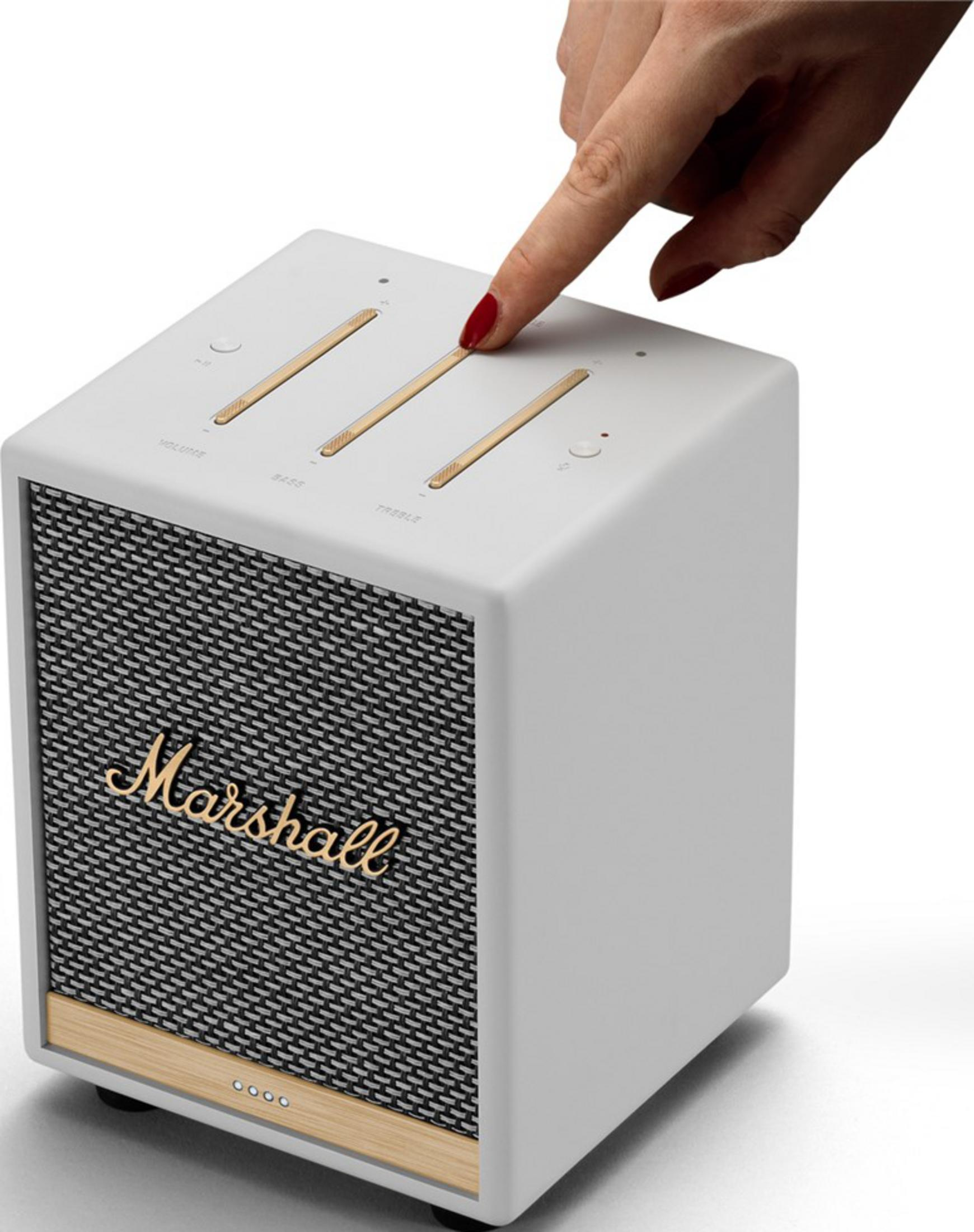 Una mano con esmalte rojo presiona un altavoz blanco Marshall.