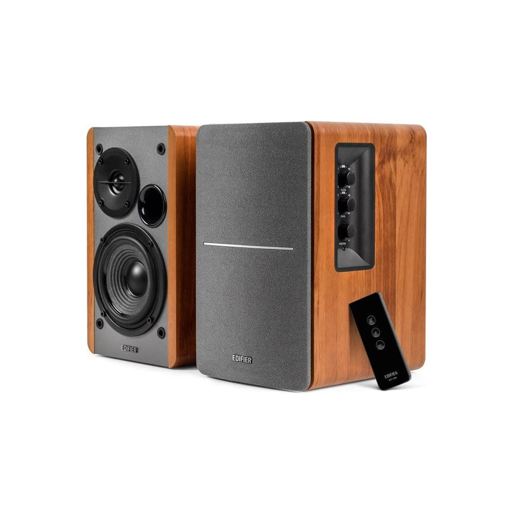 Dwa drewniane głośniki z szarymi frontami. Jeden głośnik pokazuje głośnik niskotonowy i wysokotonowy. Pilot po prawej.