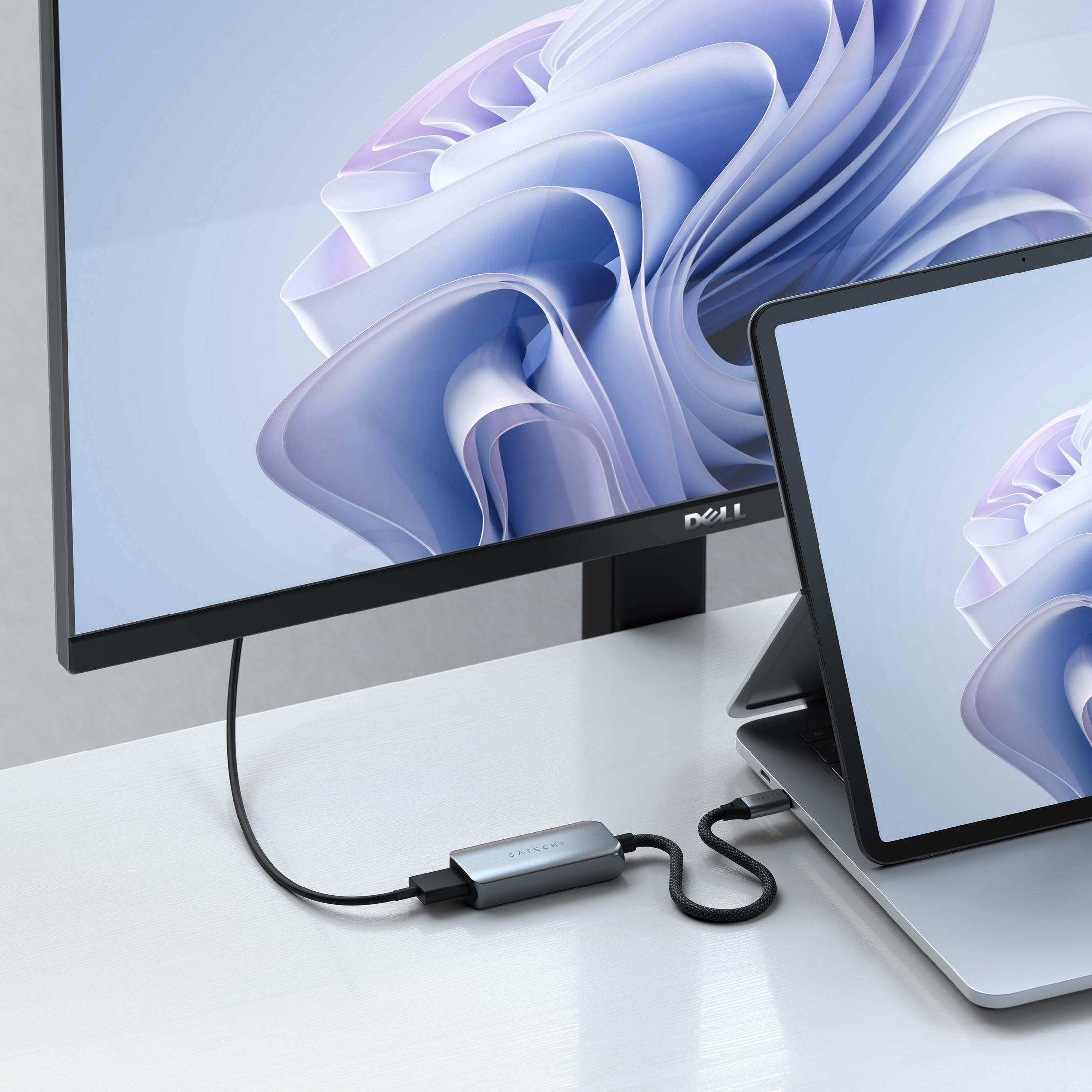 Un monitor Dell e un laptop su una scrivania bianca con sfondo astratto.