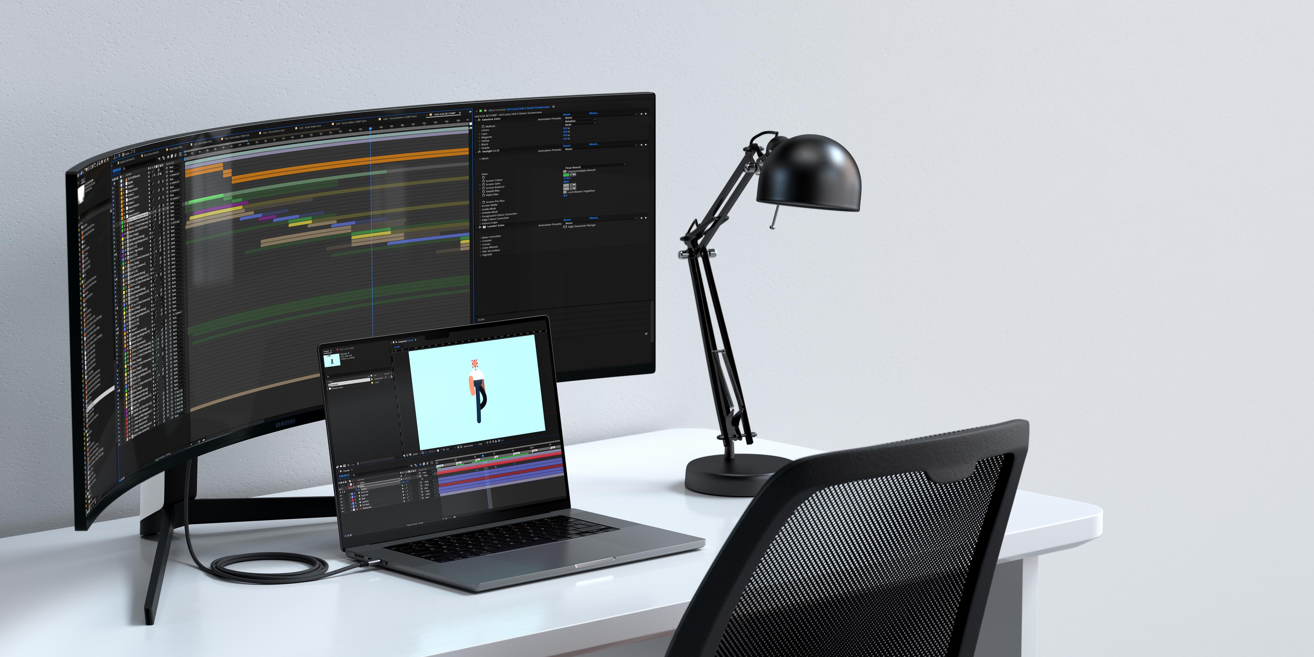 Ein Schreibtisch mit zwei Monitoren, einem Laptop, einer Lampe und einem Stuhl.