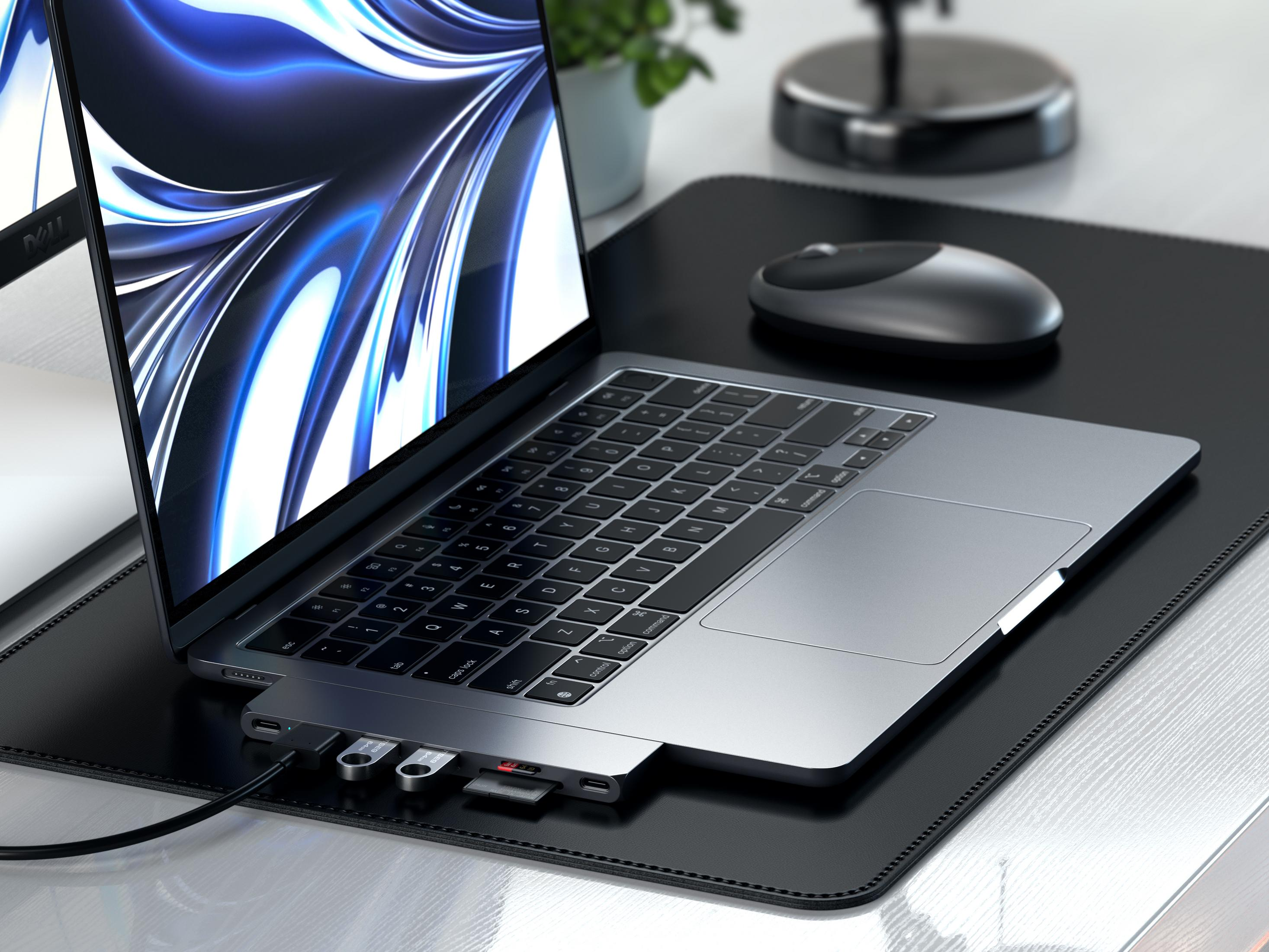 Un portátil con concentrador USB, ratón y planta conectados al fondo.