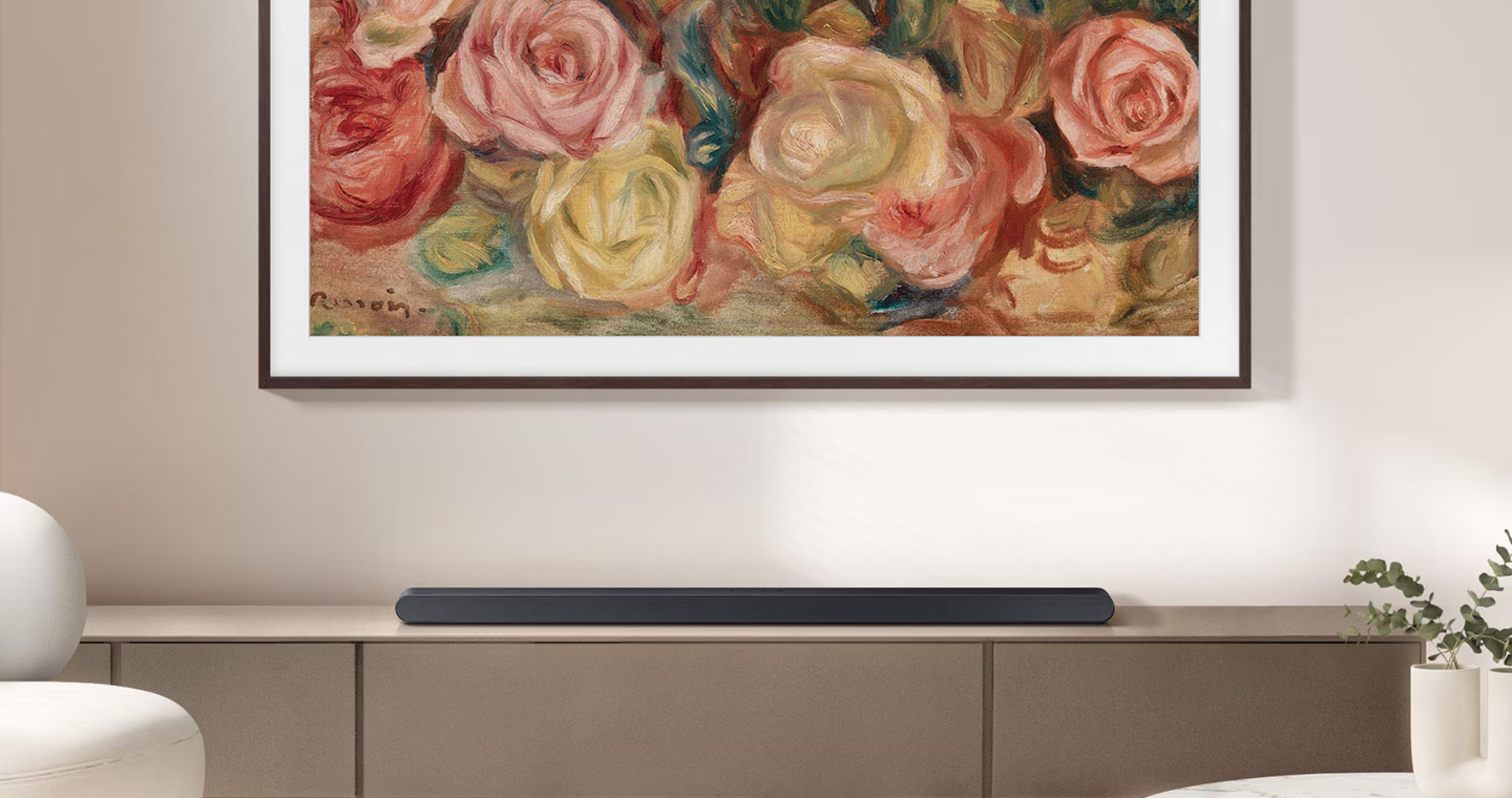 Une barre de son noire repose sur un buffet marron sous un tableau de roses.