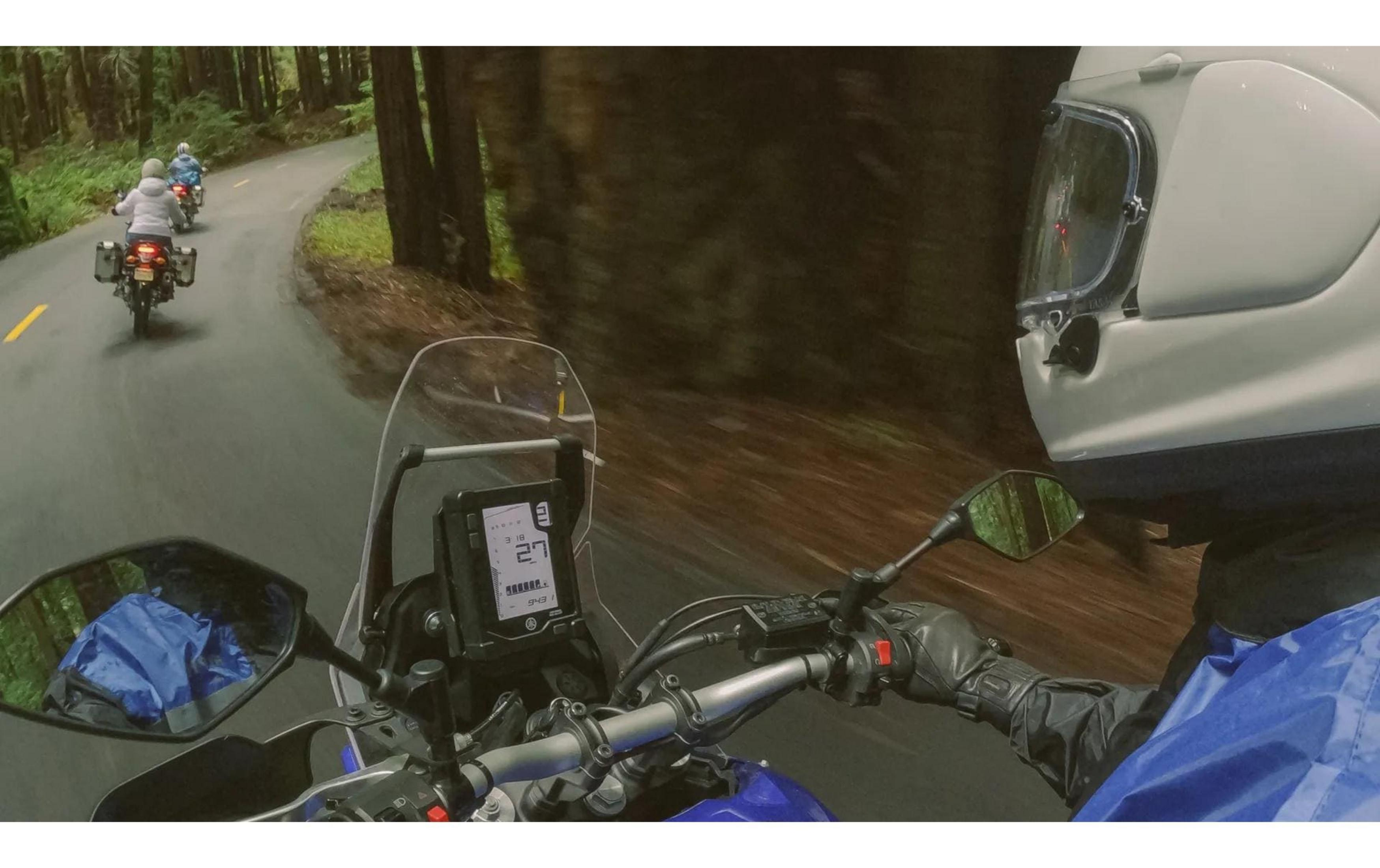 Motocykliści jadą drogą przez las. Kask jest na pierwszym planie.