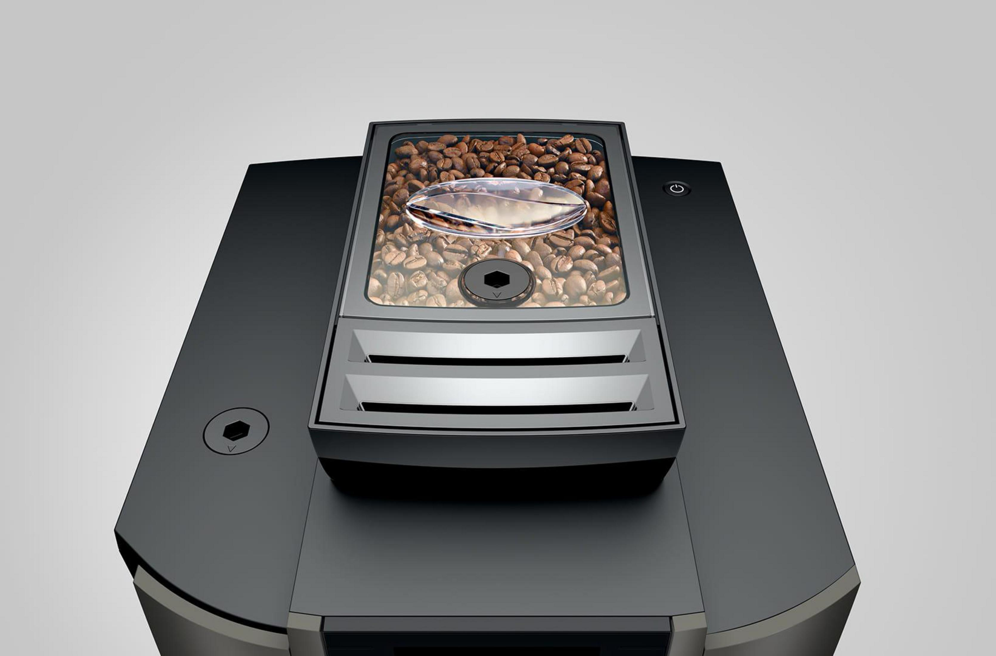 Ekspres do kawy ze zbiornikiem na ziarna, chromowanymi detalami i przyciskiem zasilania.