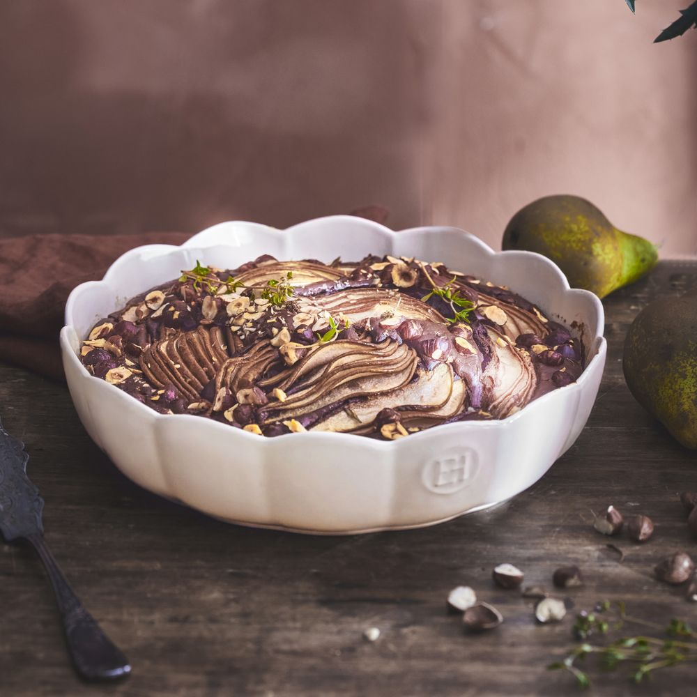 Schokoladen-Birnenkuchen mit Nüssen und Kräutern in einer weißen Schüssel.