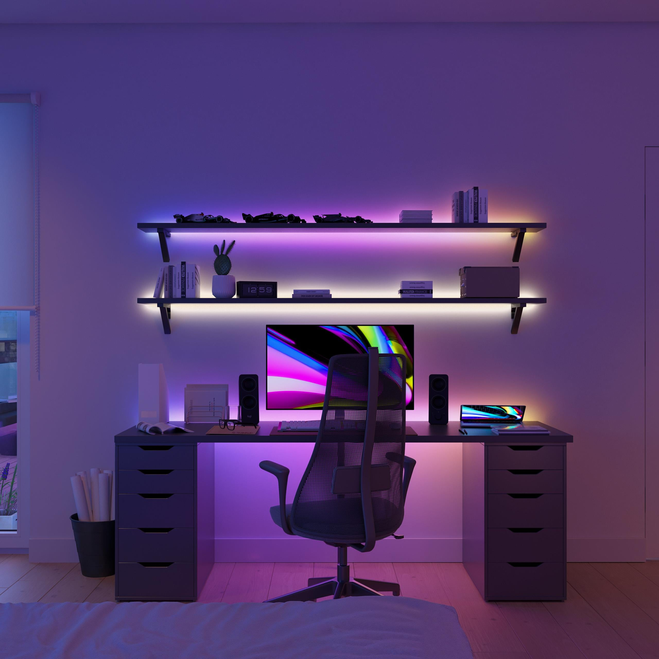 Una scrivania con computer, laptop e sedia da gaming, illuminata da strisce LED viola.