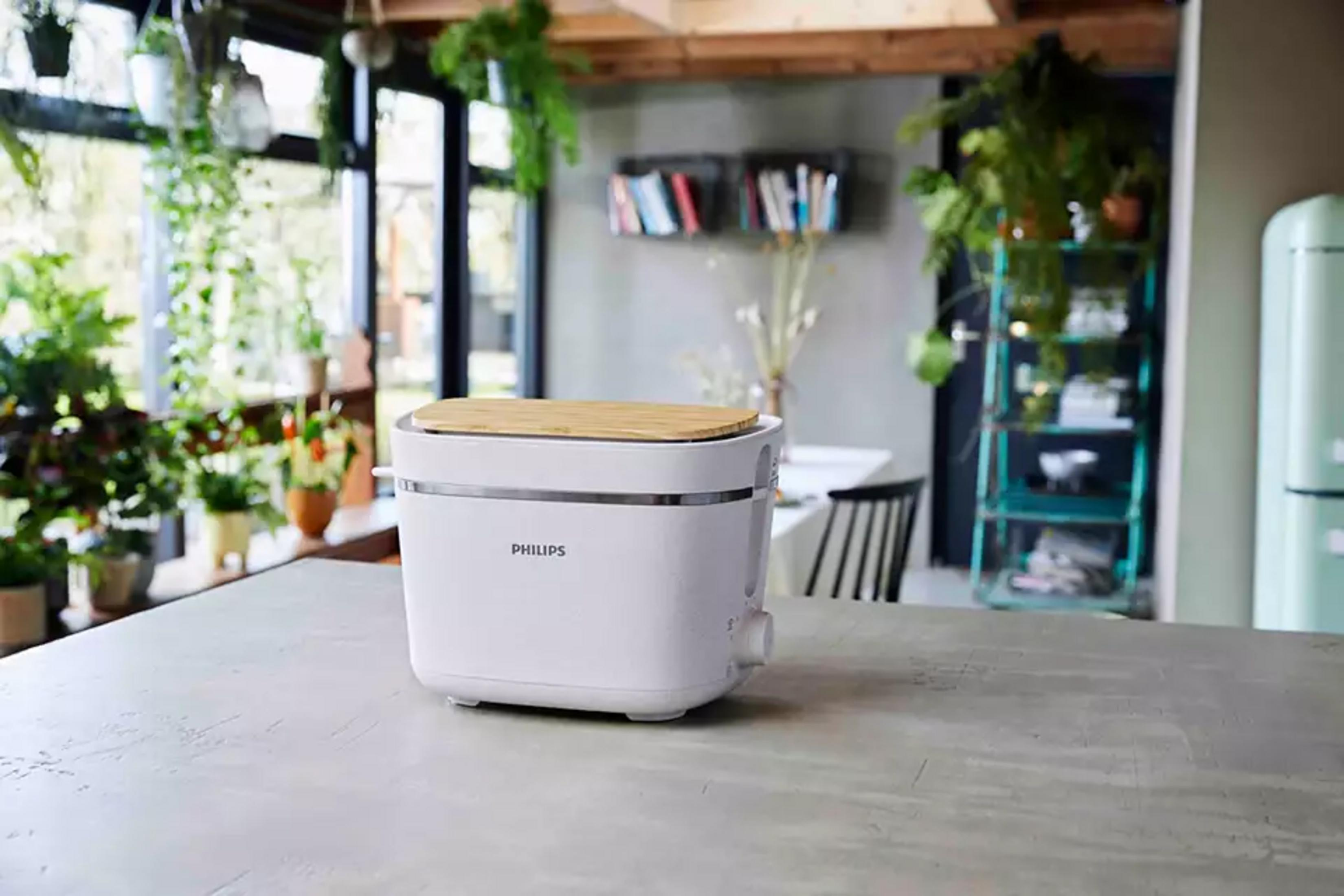 Un bollitore Philips bianco con coperchio in legno su un piano di lavoro.