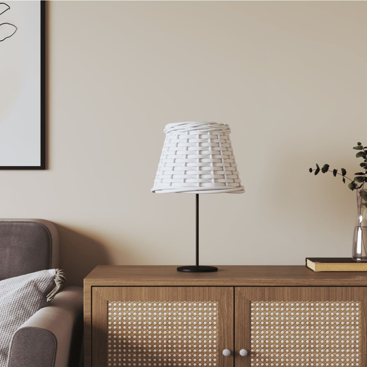 Weiße Lampe mit geflochtenem Schirm auf Holzschrank, daneben ein Sofa.