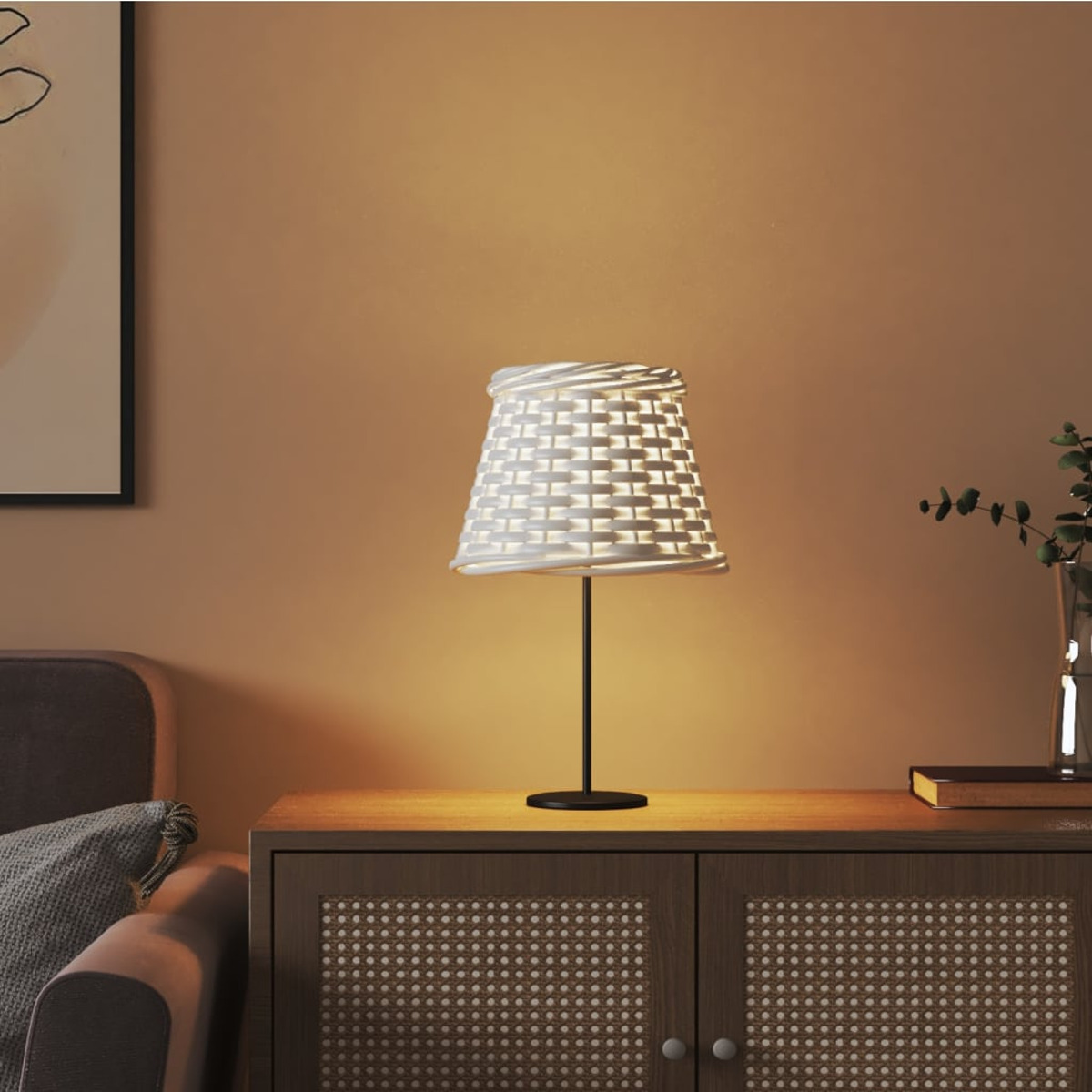 Eine weiße Korbtischlampe steht auf einem Holzschrank neben einem Sessel.