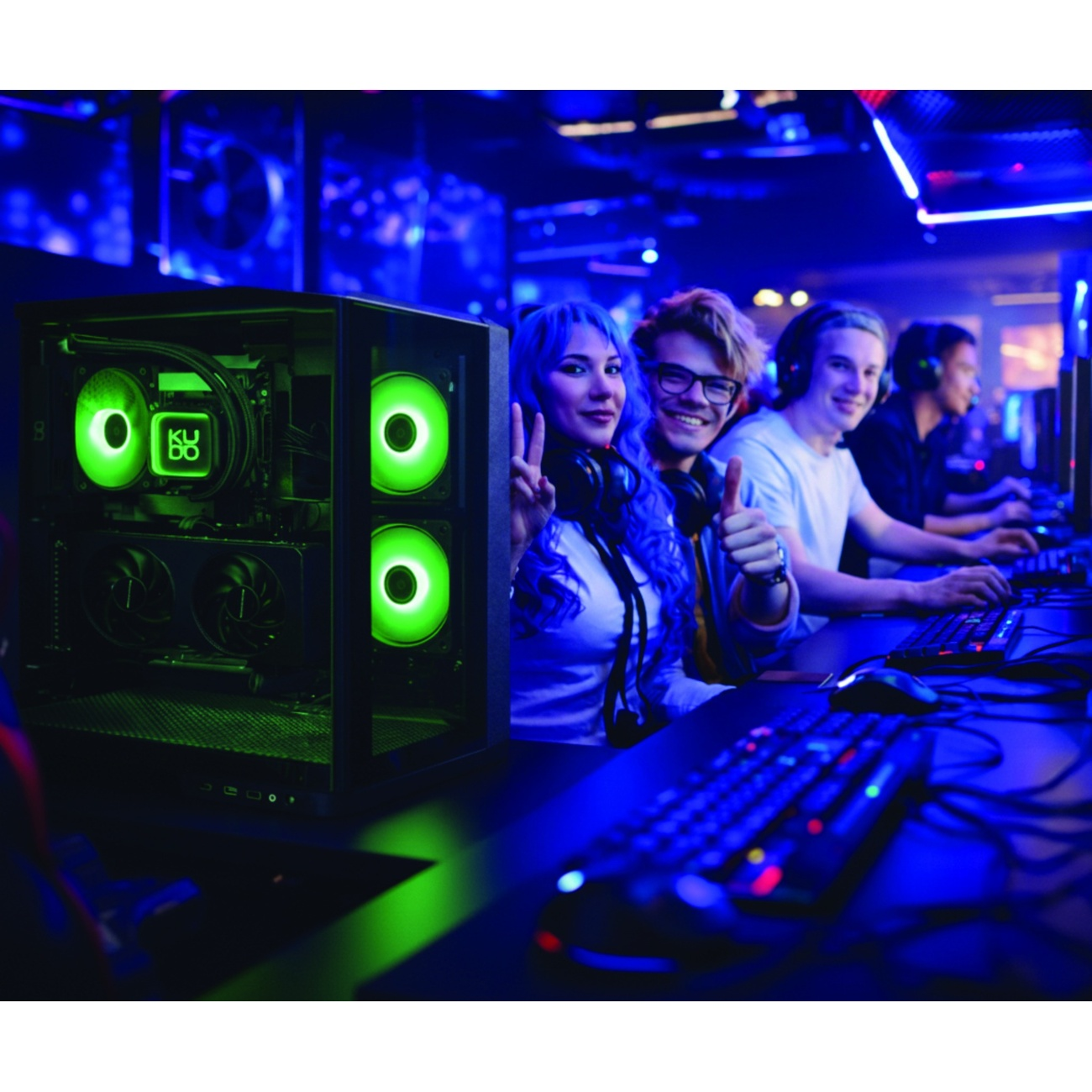 Cztery młode osoby w oświetlonym pokoju z komputerami. Po lewej komputer z zielonym podświetleniem.