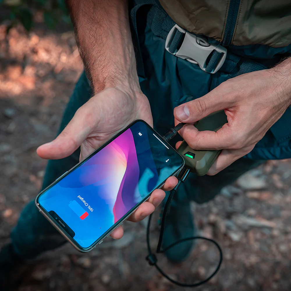 Hände laden ein Smartphone mit einem Powerbank auf, das Gerät ist grün.