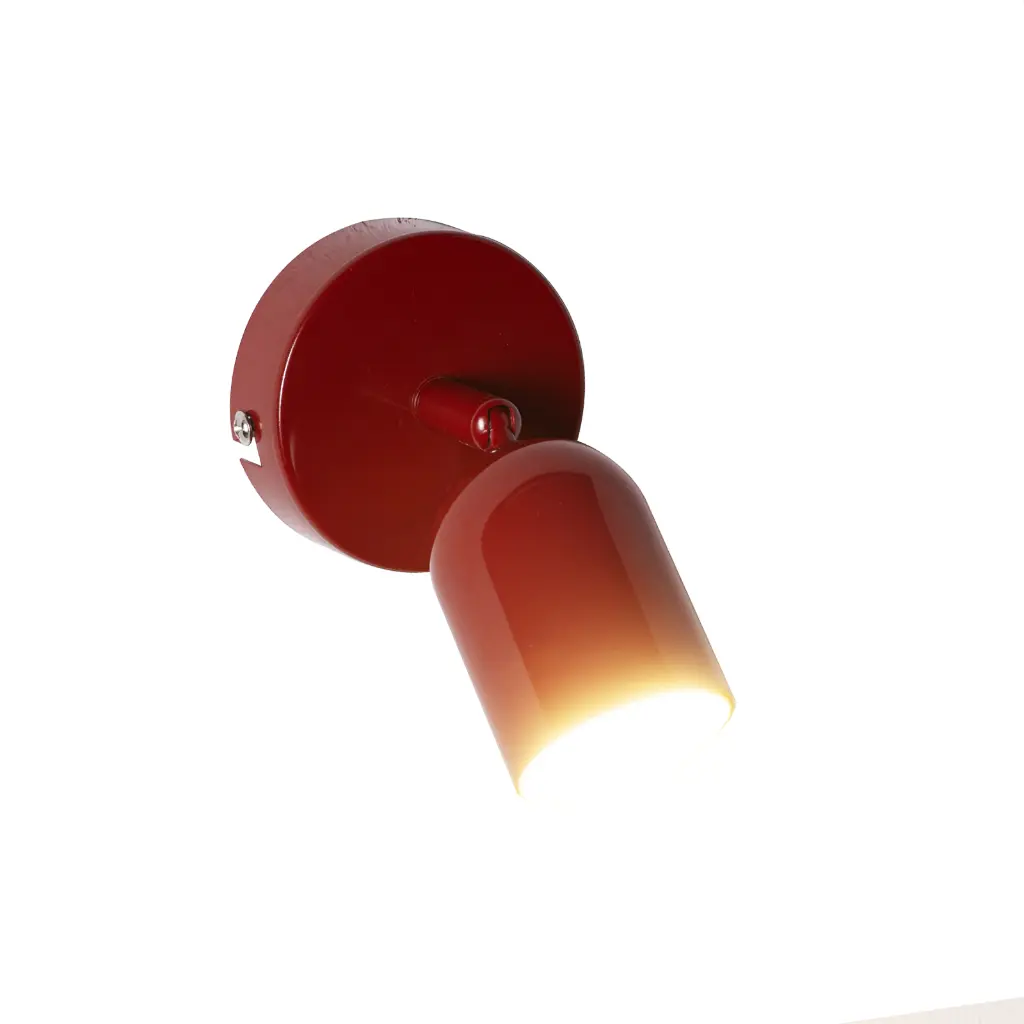 Una lámpara de pared roja moderna con foco direccional está montada en pared blanca.