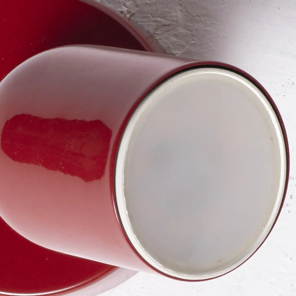 Taza roja sobre un platillo. Vista de cerca.