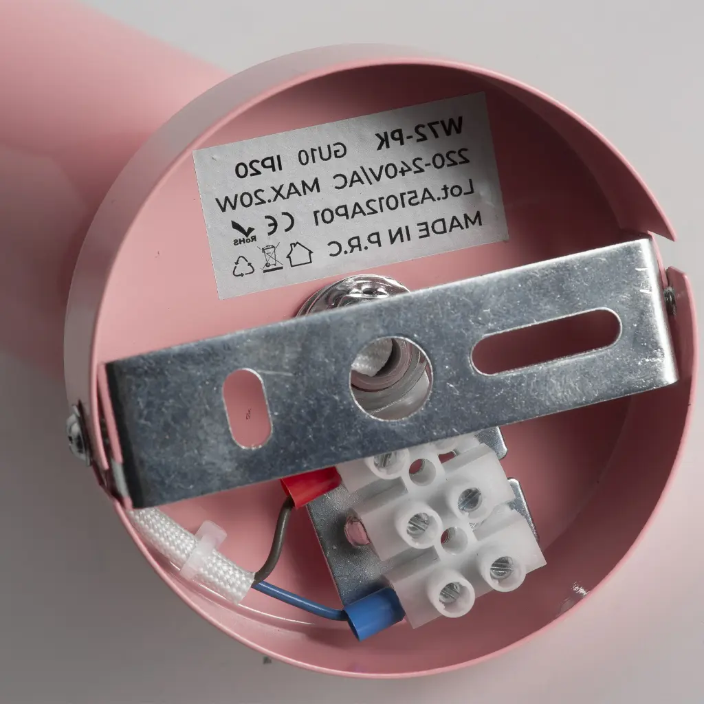 Base de lámpara rosa con conexiones eléctricas y un soporte de montaje plateado.