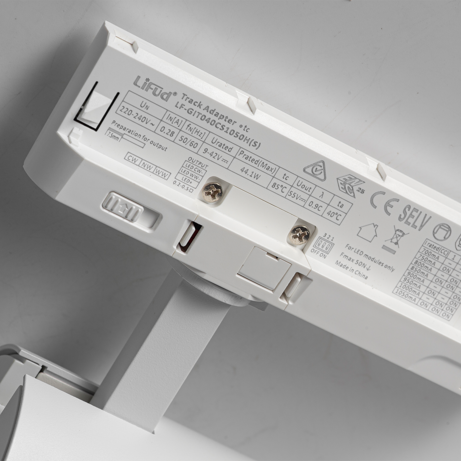 Un controlador LED blanco con etiquetas y interruptores. Se ven detalles de voltaje y potencia.