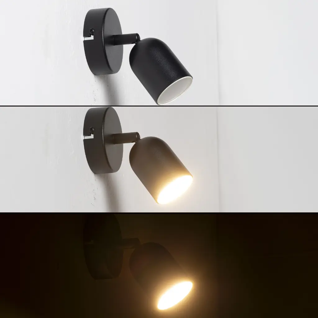 Un foco de pared negro y orientable está montado en una pared blanca.