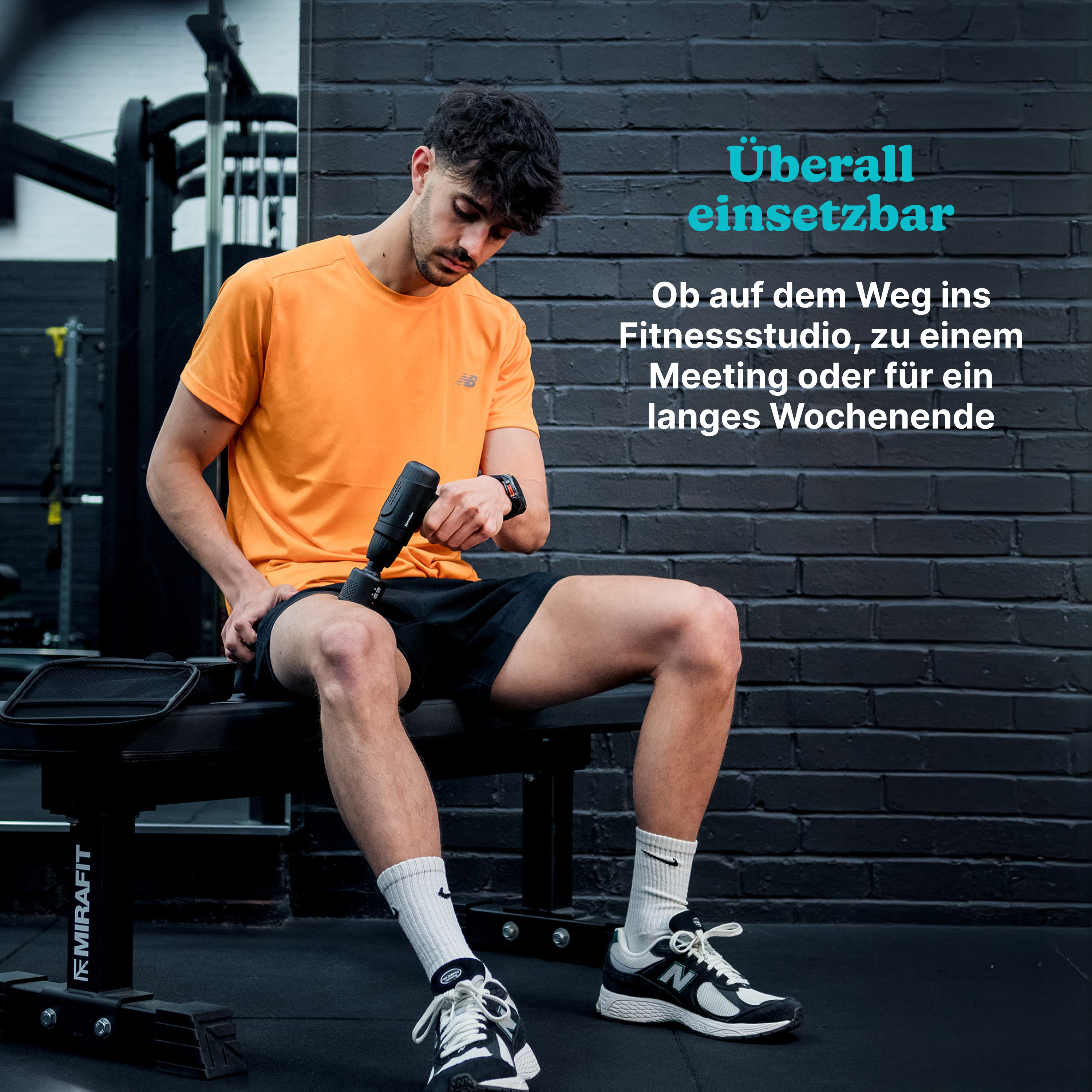 Mann im Fitnessstudio mit Massagepistole. Orange Shirt, schwarze Shorts.