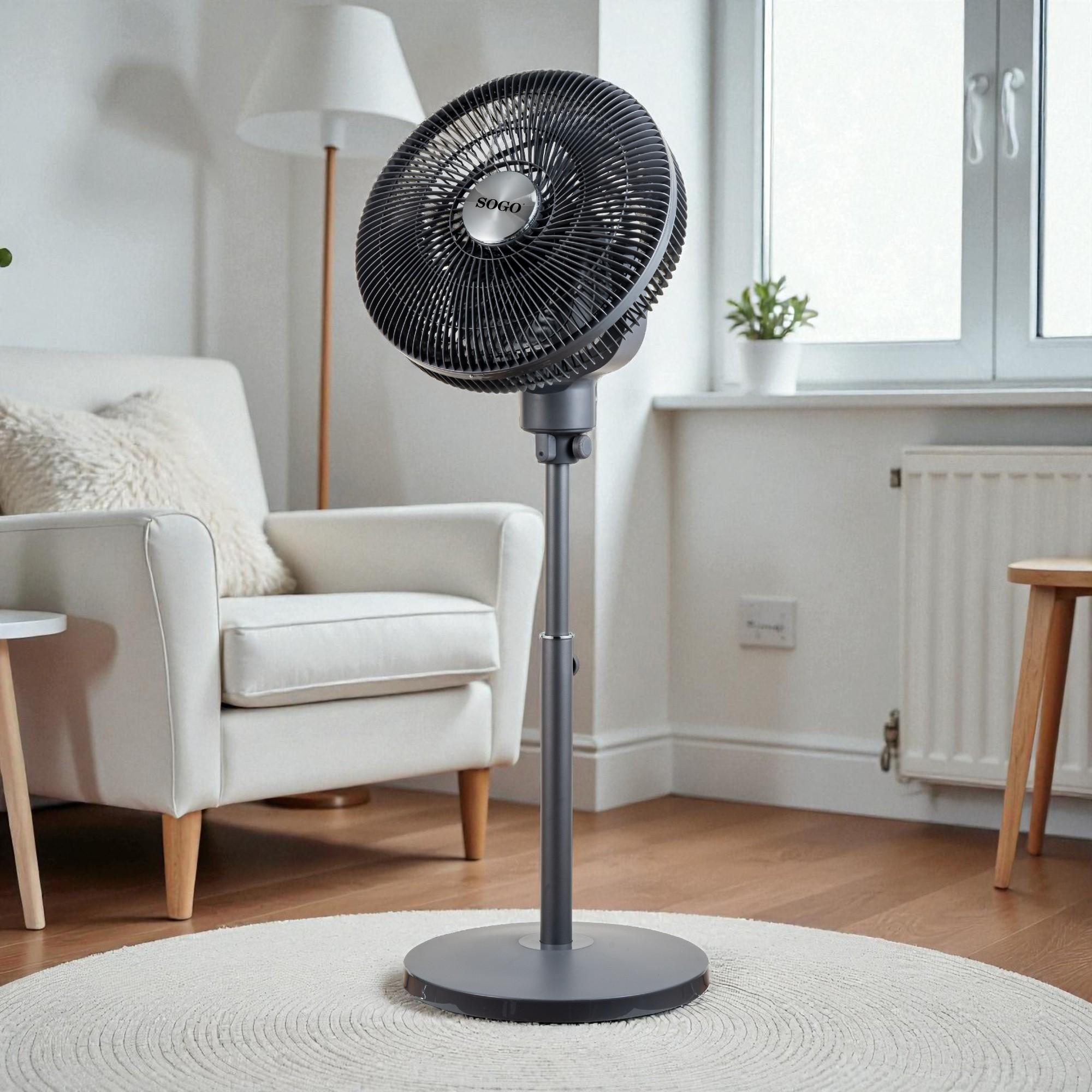 Un ventilador de pie oscuro está sobre una alfombra redonda frente a un sillón blanco.