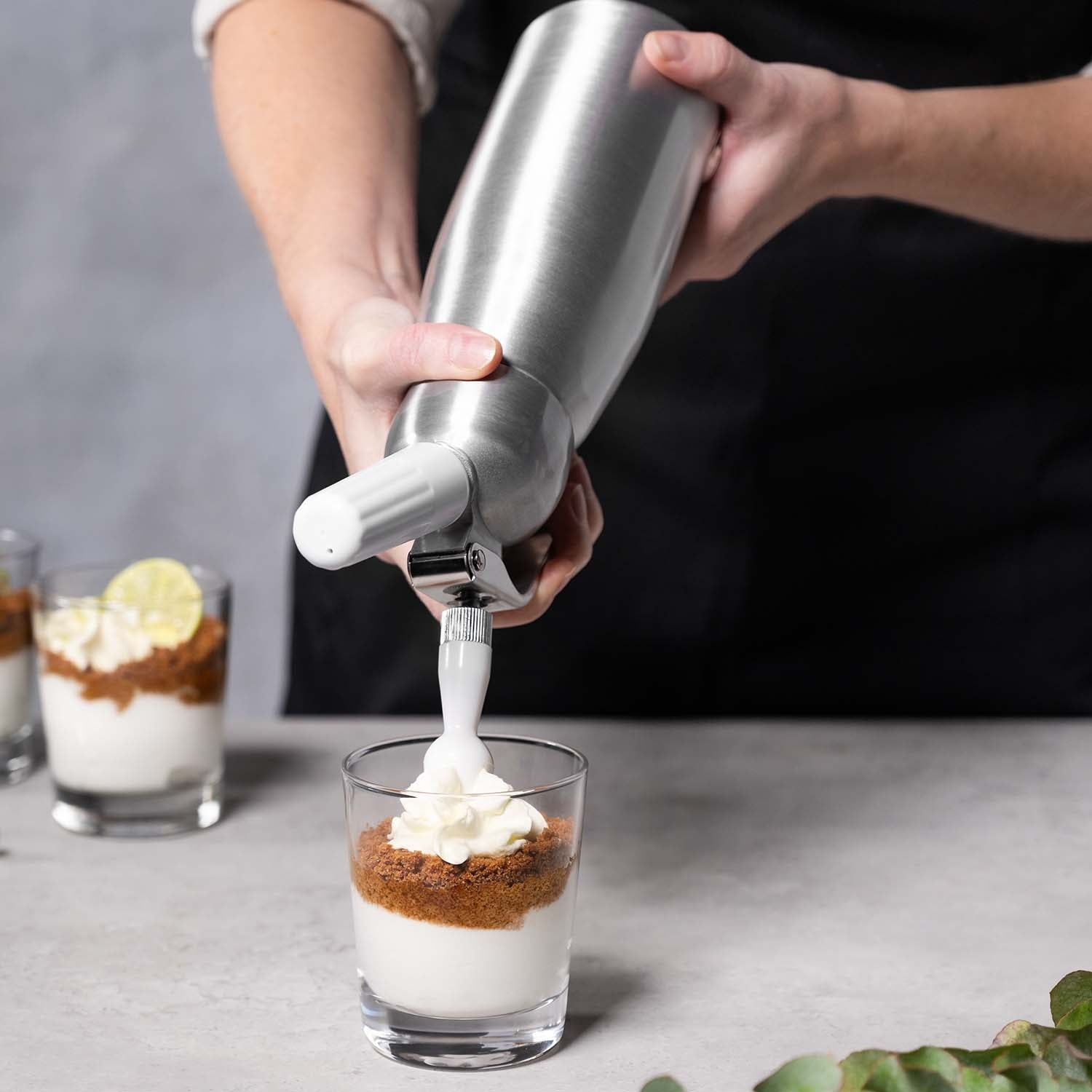 Room wordt uit een slagroomspuit in een glas dessert gespoten.