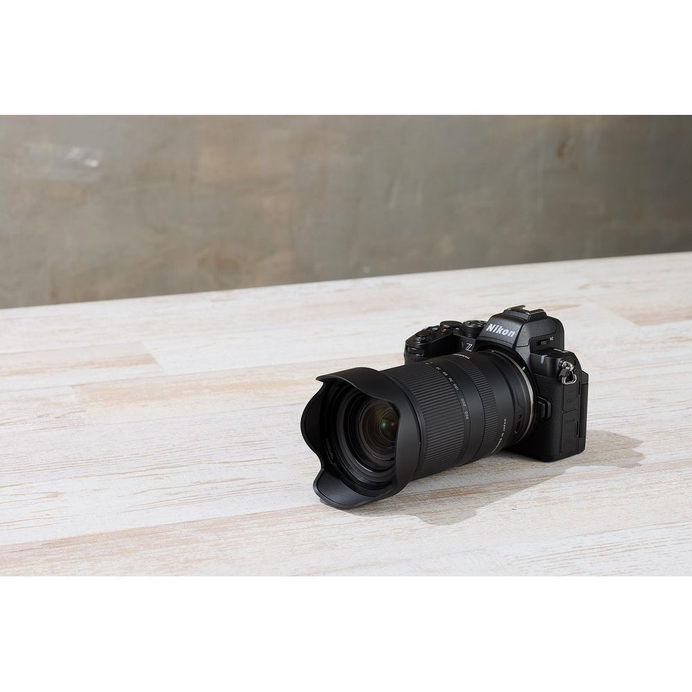 Una fotocamera Nikon nera con un obiettivo grande poggia su un tavolo di legno.