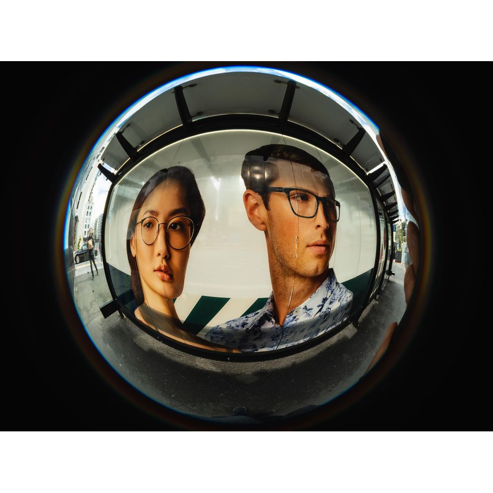 A man and a woman wearing glasses on a poster in a fisheye lens.
