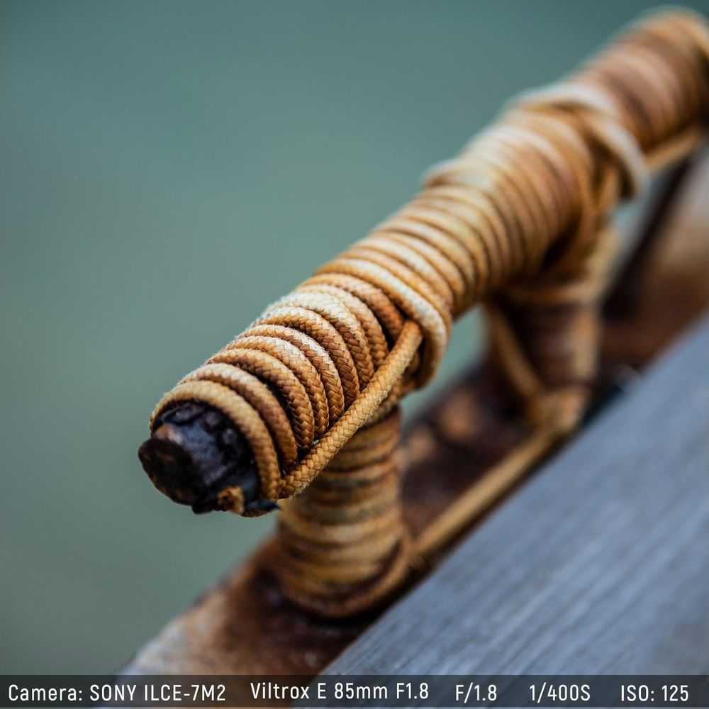 Una corda avvolta attorno a un oggetto di legno scuro, con sfondo sfocato.