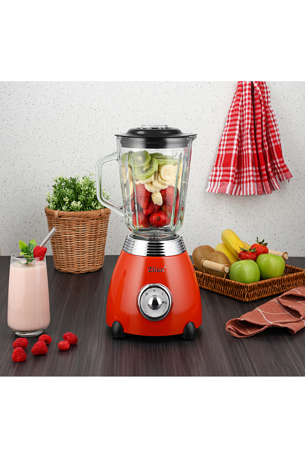 Smoothie bardağı ve meyve sepeti yanında, meyve dolu kırmızı blender.