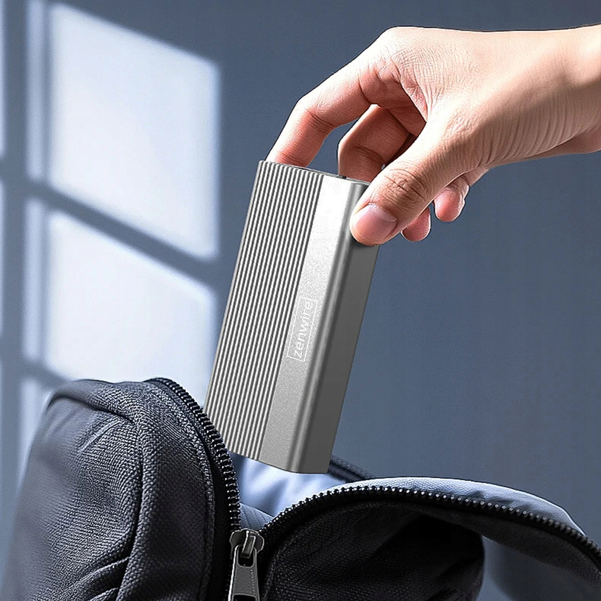 Ręka wkłada srebrny dysk twardy do czarnej torby.