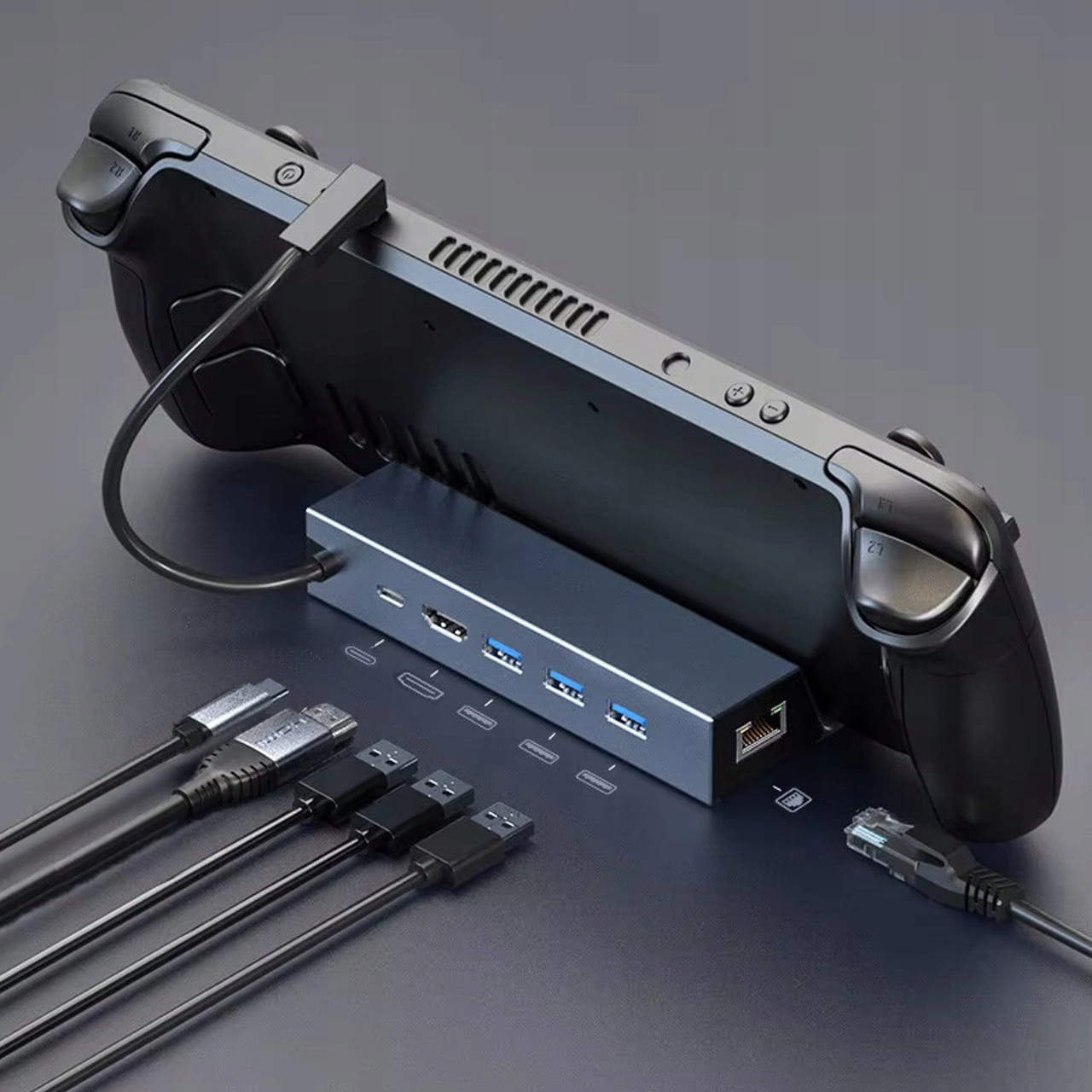 Czarna ręczna konsola do gier jest podłączona do srebrnego huba z wieloma portami i kablami.