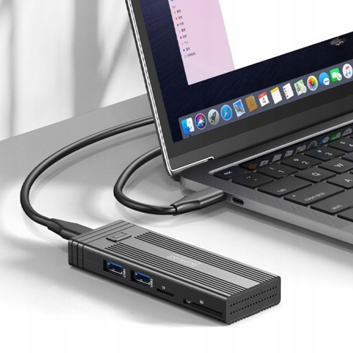 Czarny hub USB-C z portami jest podłączony do srebrnego laptopa na biurku.