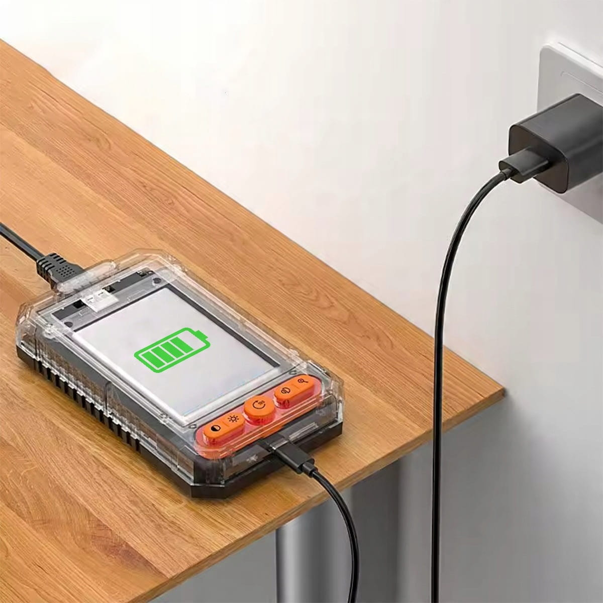 Przezroczyste urządzenie z ikoną baterii ładuje się na drewnianym stole.