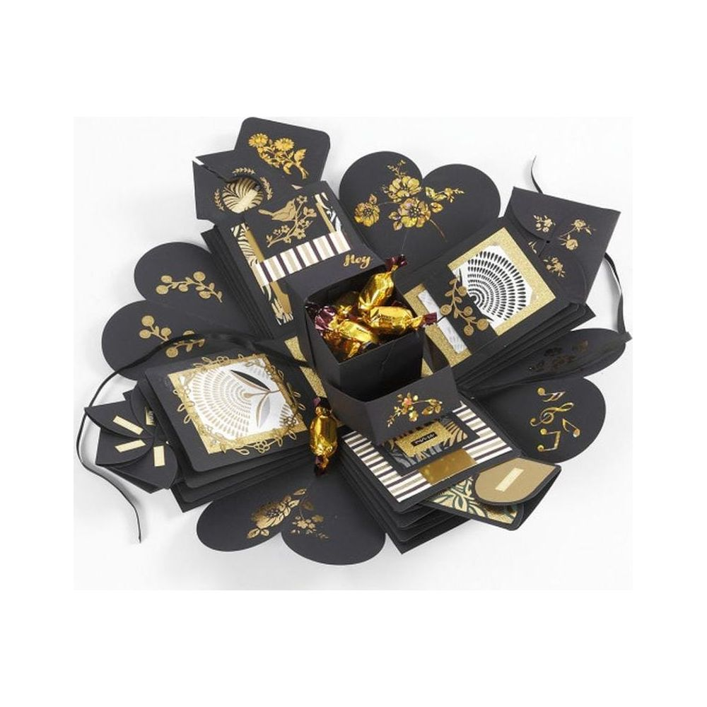 Eine schwarze Explosionsbox mit goldenen Verzierungen und Pralinen.