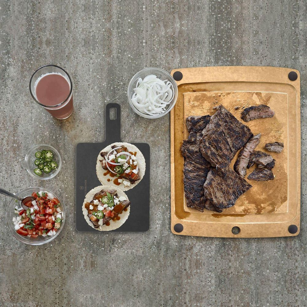 Gegrilltes Steak, Tacos, Salsa, Zwiebeln und ein Getränk auf Betonoberfläche.