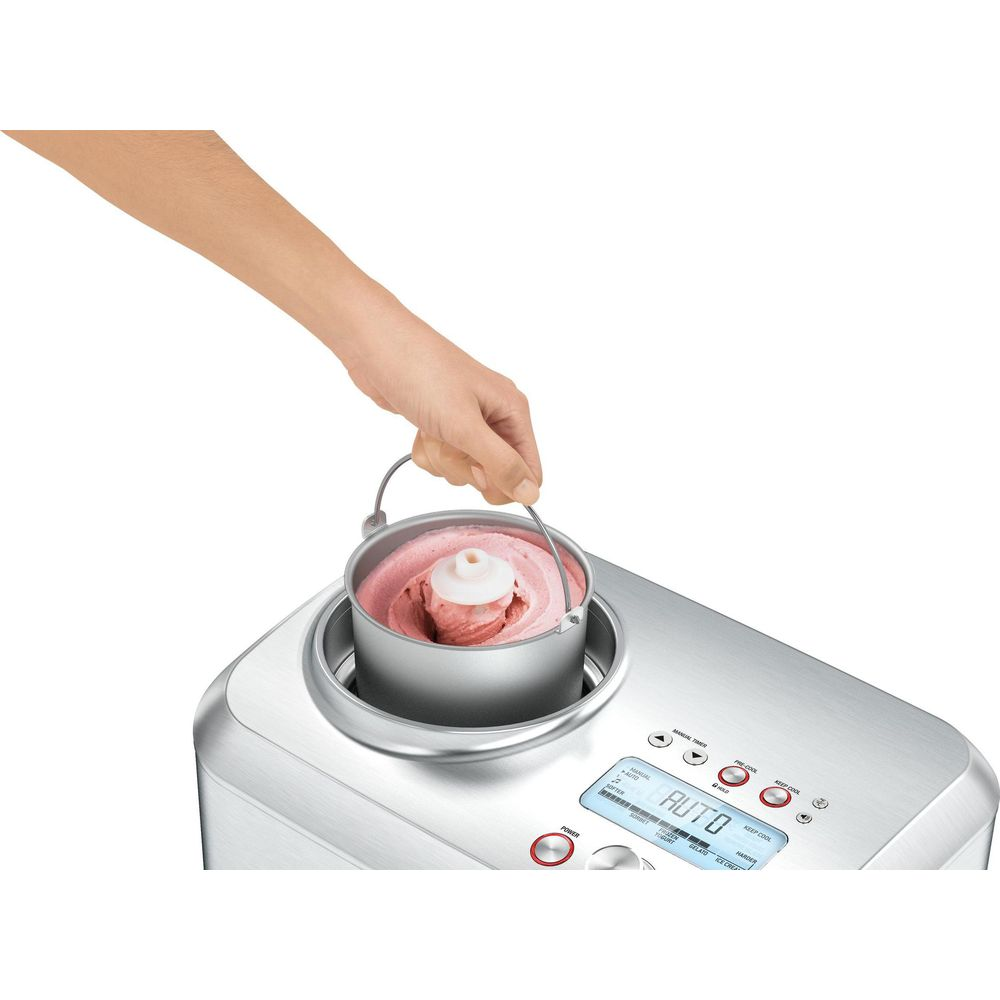 Eine Hand hebt einen Eisbehälter mit rosa Eis aus einer Eismaschine.