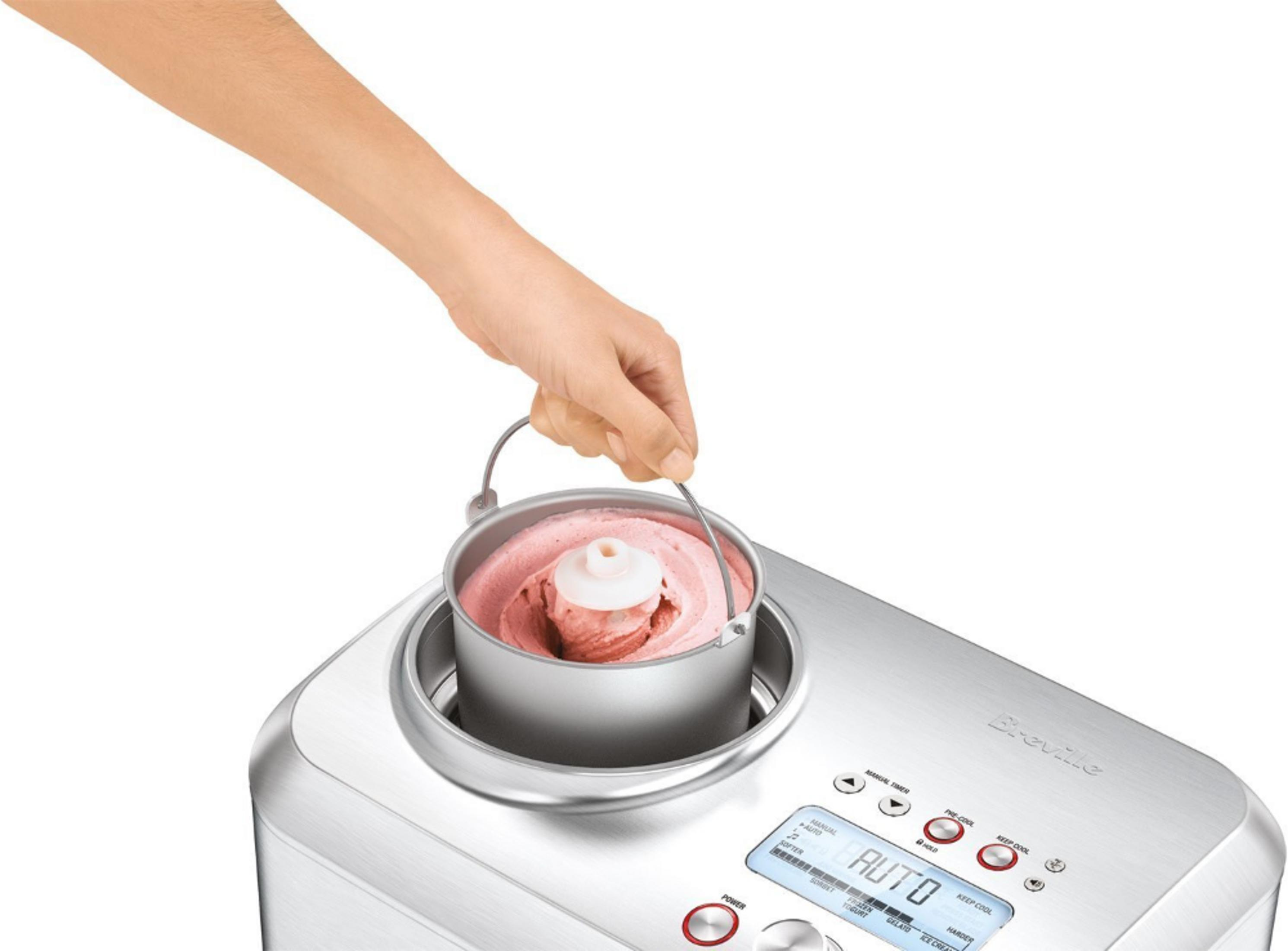 Eine Hand hebt eine Schüssel mit Eiscreme aus einer silbernen Eismaschine.