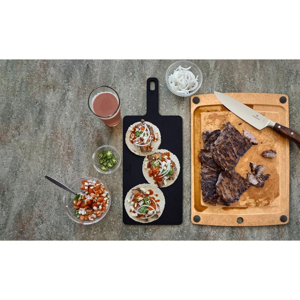 Tacos mit Fleisch, Zwiebeln, Tomaten und Koriander auf schwarzem Brett, daneben Bier, Salsa, Jalapenos.