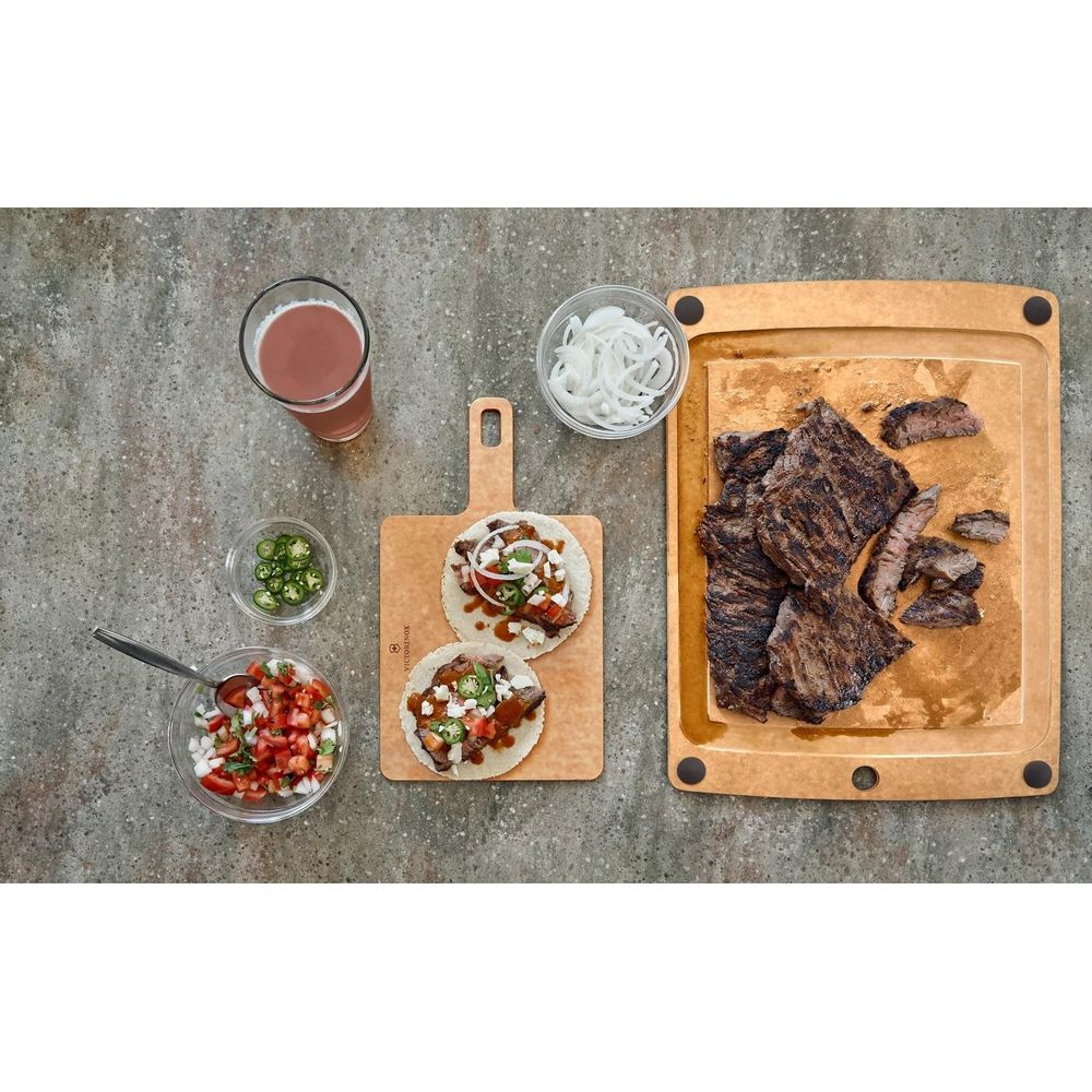 Gegrilltes Fleisch auf einem Schneidebrett mit Tacos, Salsa, Jalapeños und Bier.