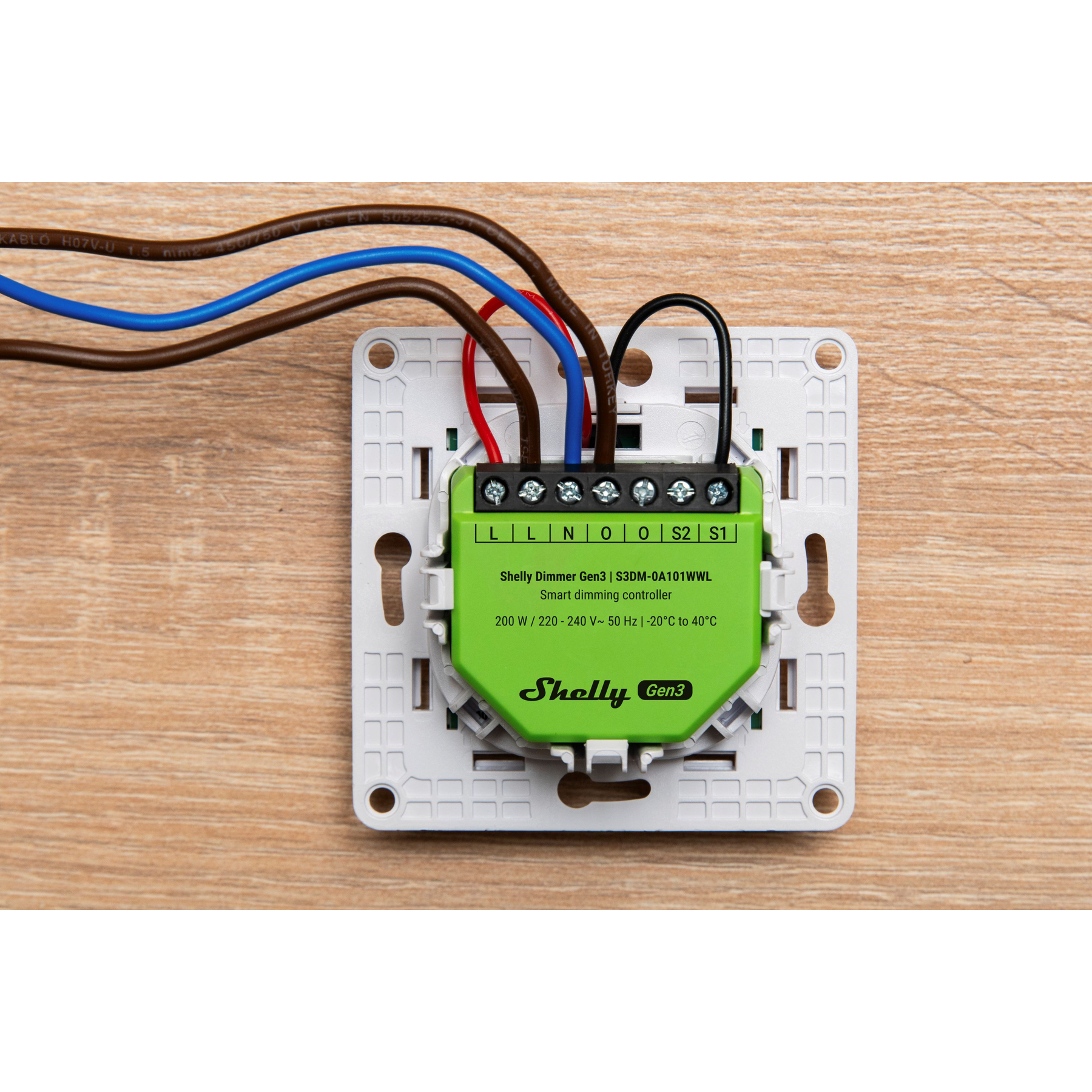 Un Shelly Dimmer Gen3 con cables sobre superficie de madera.