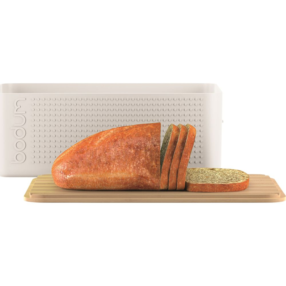 Ein angeschnittenes Brot liegt auf einem Holzbrett neben einem weißen Brotkasten.