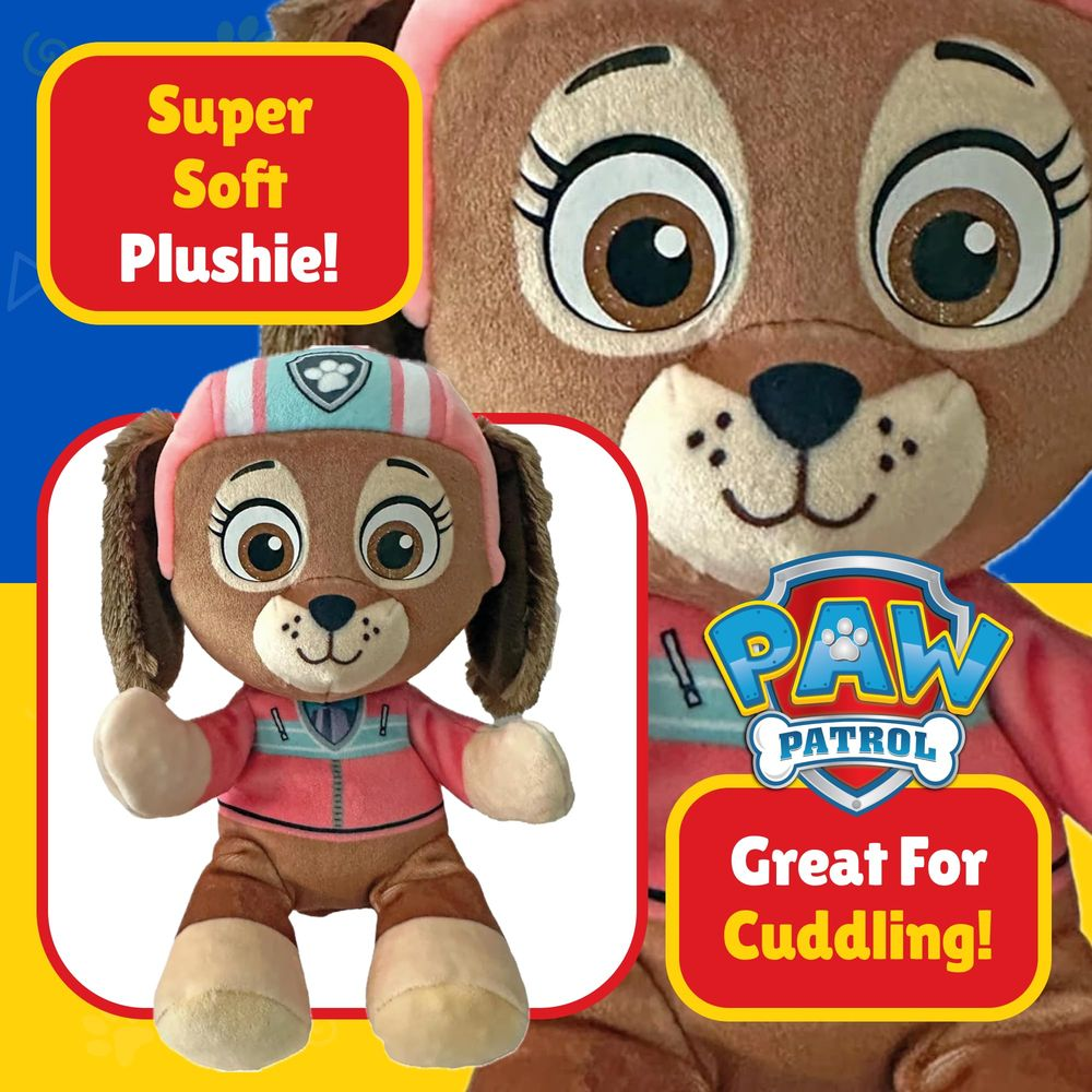 Ein brauner Paw Patrol Plüschhund in rosa Kleidung, sitzend.