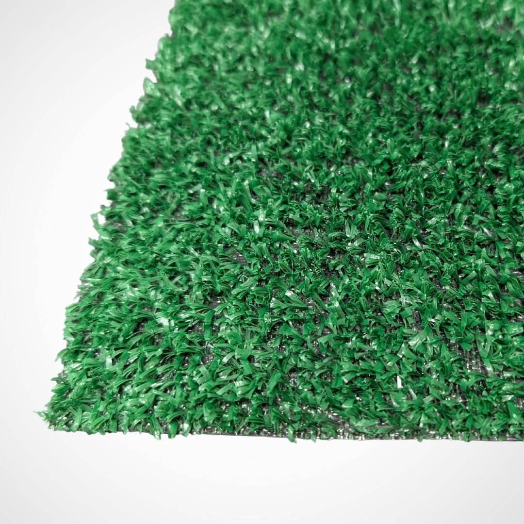 Primer plano de césped artificial verde sobre fondo blanco.
