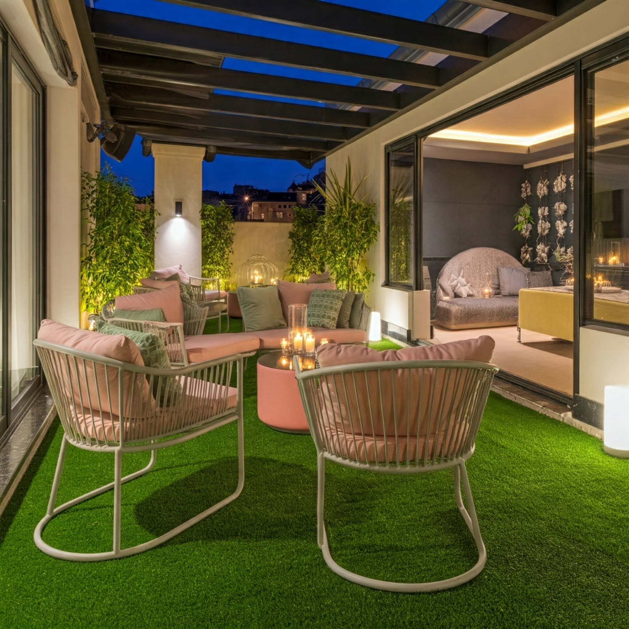 Un patio amueblado con césped artificial, muebles de salón y velas por la noche.