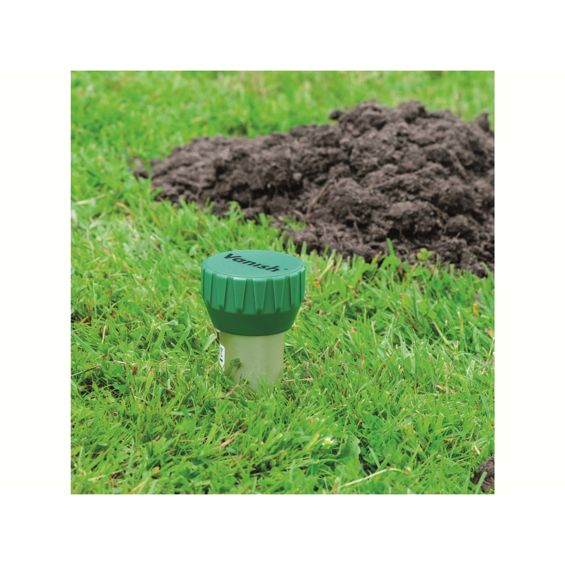 Ein grüner Behälter steht im Gras neben einem Erdhaufen.