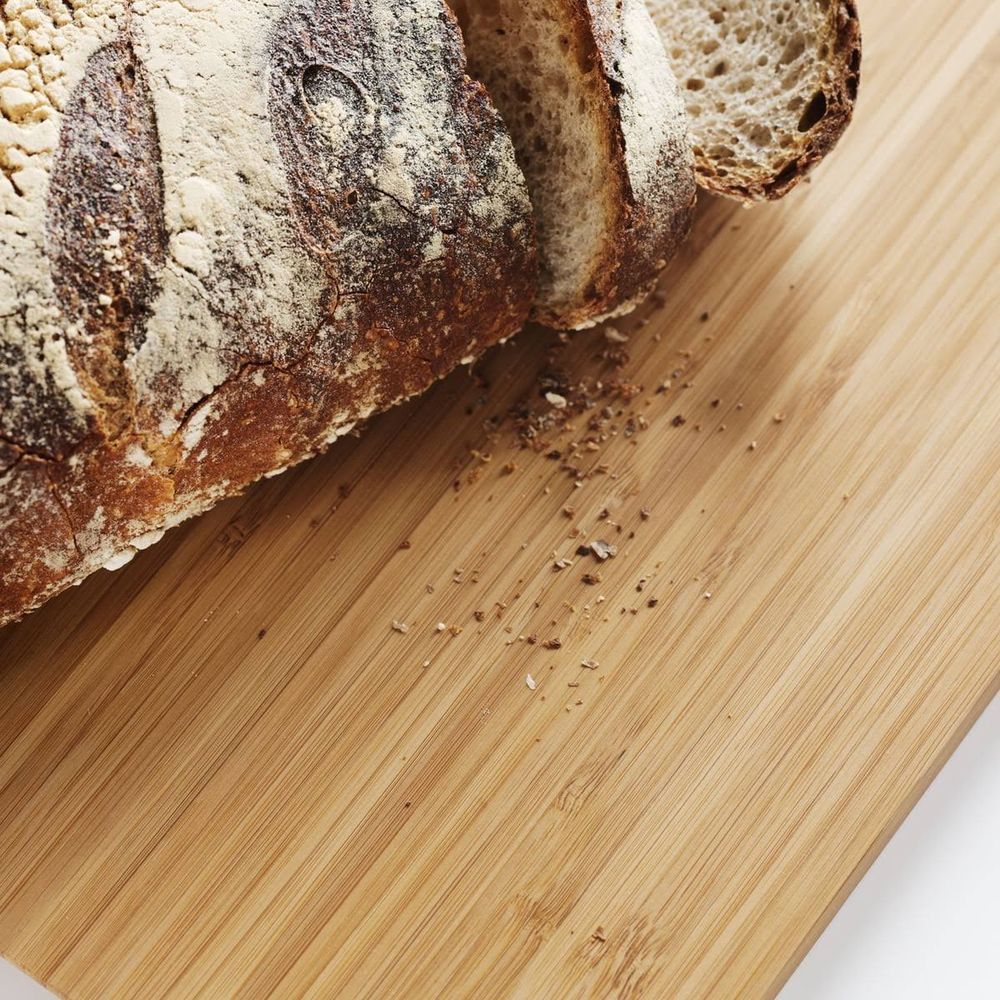 Ein Laib Brot, in Scheiben geschnitten, liegt auf einem Holzbrett.