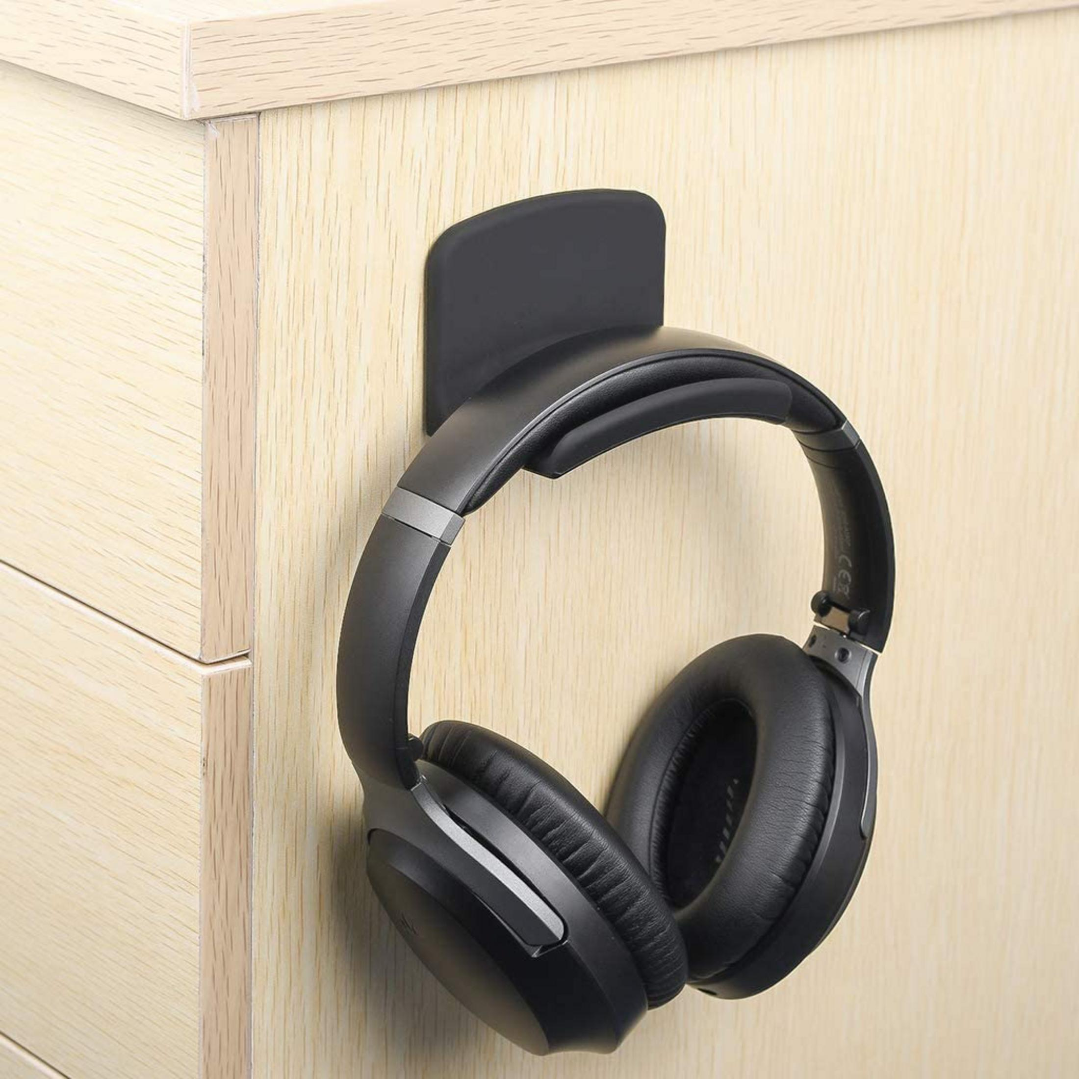 Casque noir suspendu à un support noir sur une surface en bois.