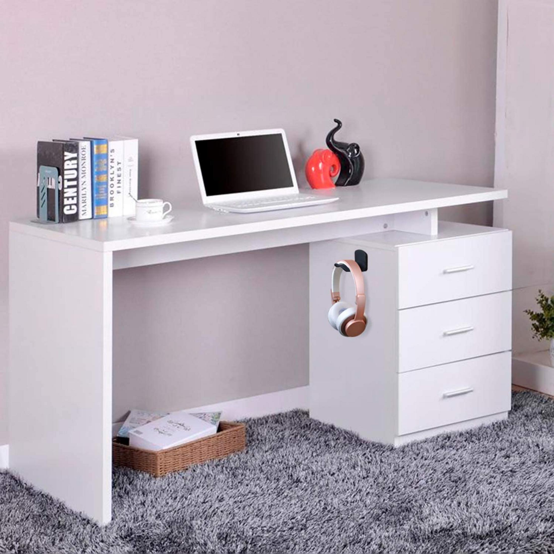 Un bureau blanc avec un ordinateur portable, des livres, une tasse, des écouteurs et des tiroirs.